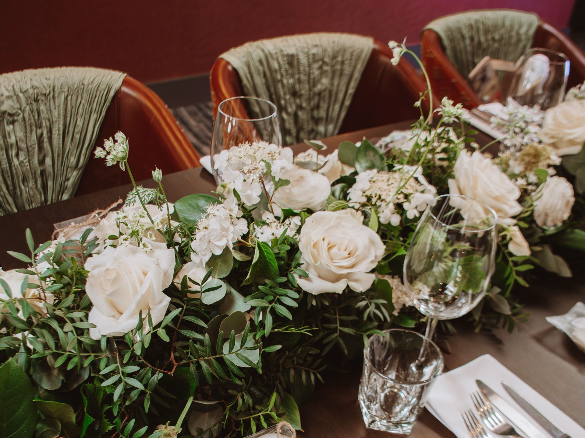 An elegant wedding table setting with white roses, greenery and personalised gifts