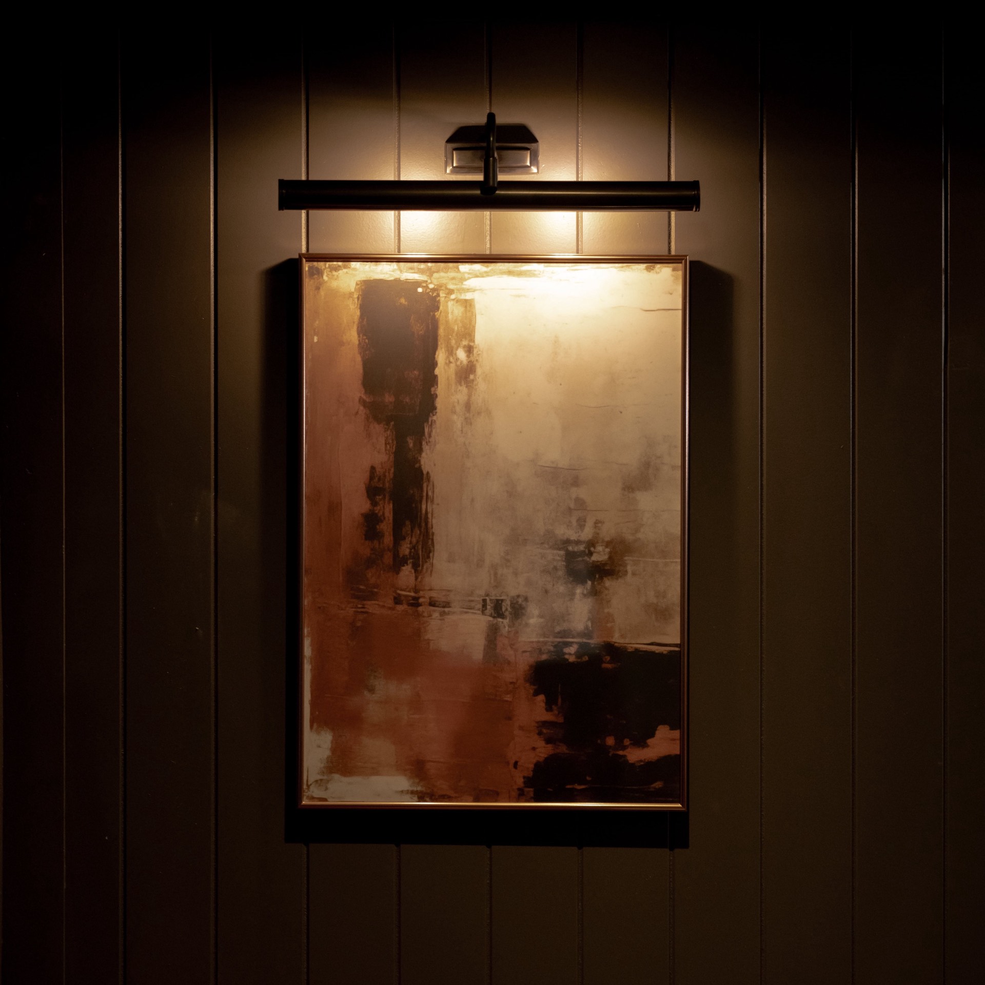 An abstract painting with a picture light on a dark panelled wall