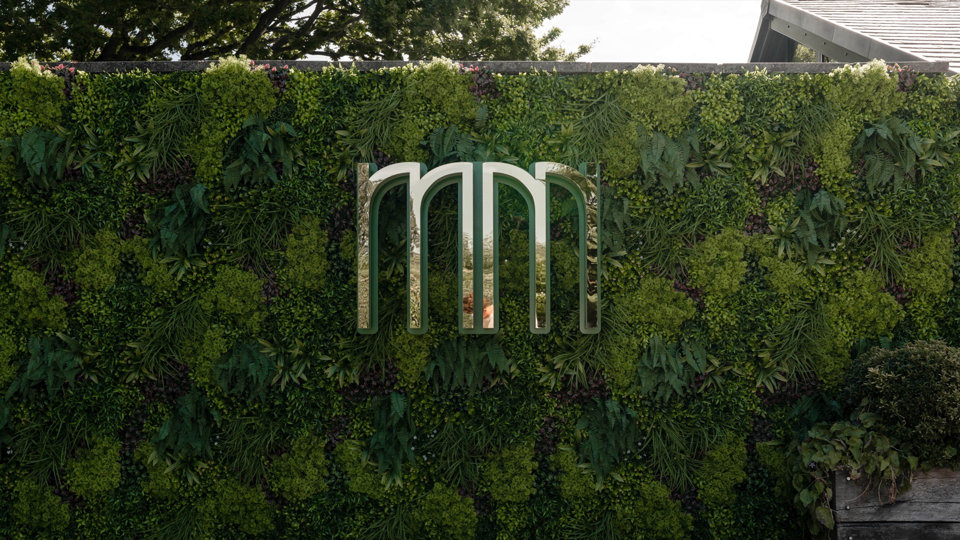 The metallic Mason's logo on a green plant wall