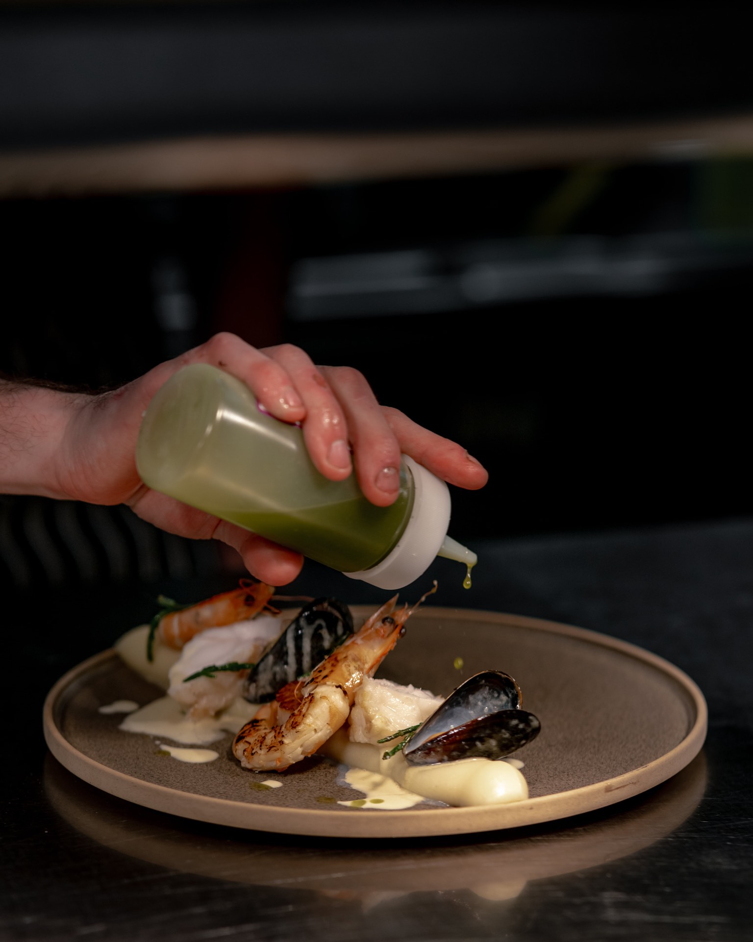A chef drizzling sauce over a dish