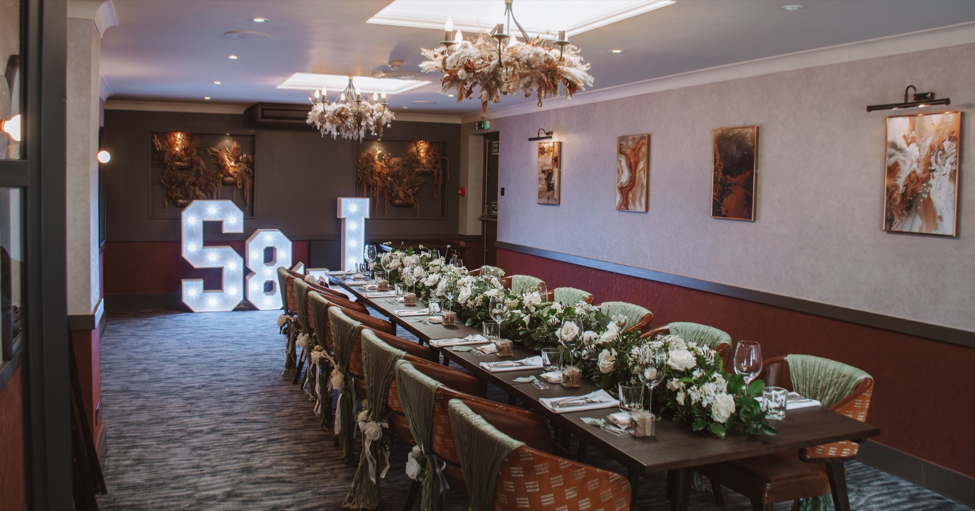A long wedding table dressed with greenery and light-up letters at Mason's